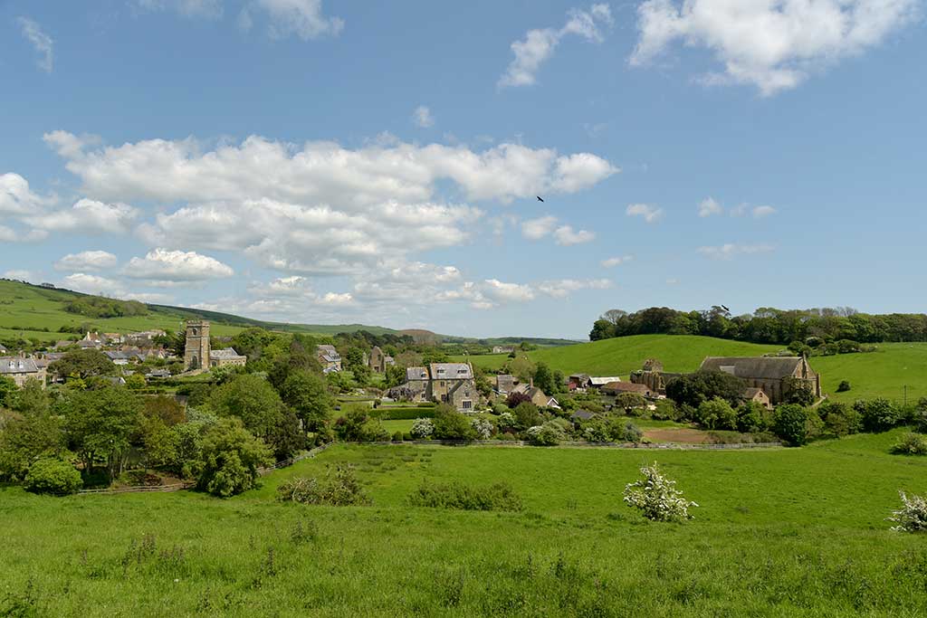 Abbotsbury village. St Nicholas' Church on the left with the abbey ruins in the centre. The Children's Farm is on the right.