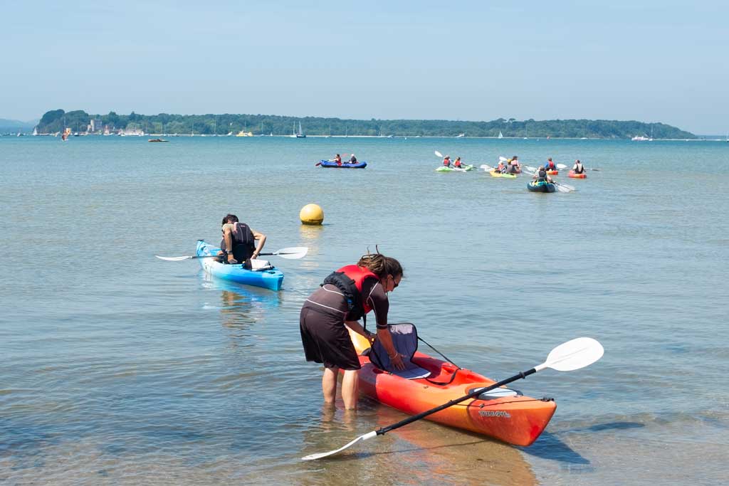 Kayaking in Poole Harbour. This location is ideal for beginners as the water close to the shore remains shallow and calm. More experienced kayakers can paddle around Brownsea Island.